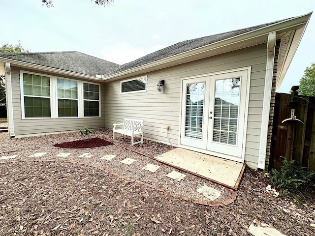 rear view of property featuring a shingled roof, french doors, and fence