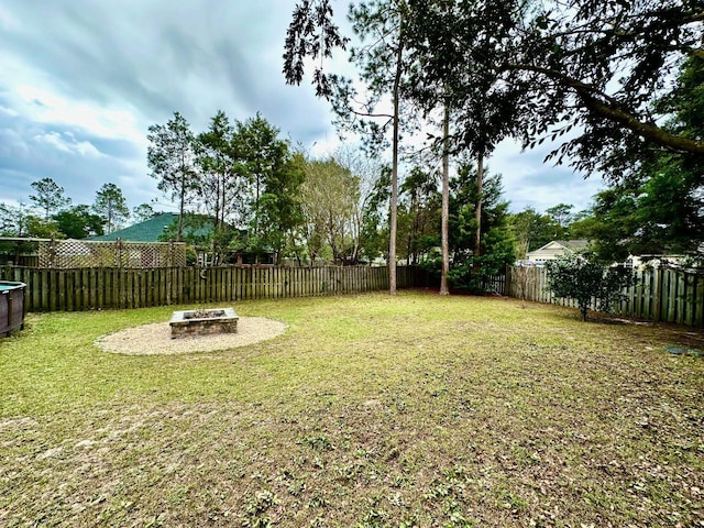 view of yard featuring a fenced backyard and a fire pit