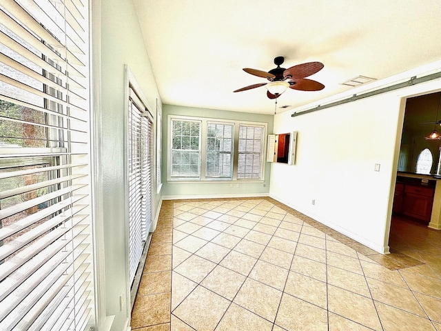 interior space featuring light tile patterned floors, a barn door, visible vents, baseboards, and ceiling fan