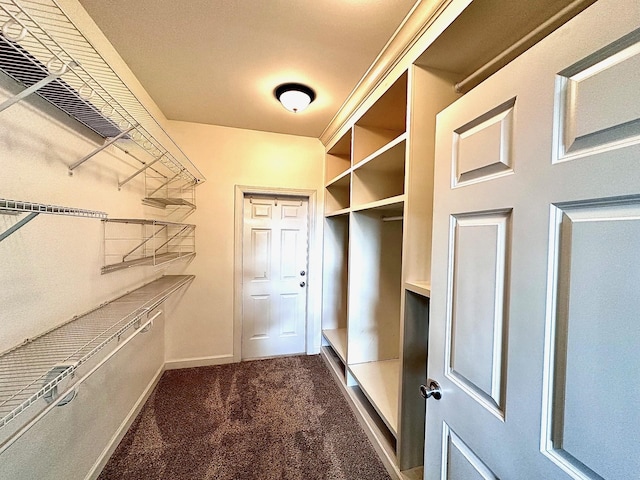 mudroom featuring dark colored carpet and baseboards