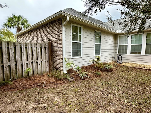 view of side of home featuring brick siding and fence