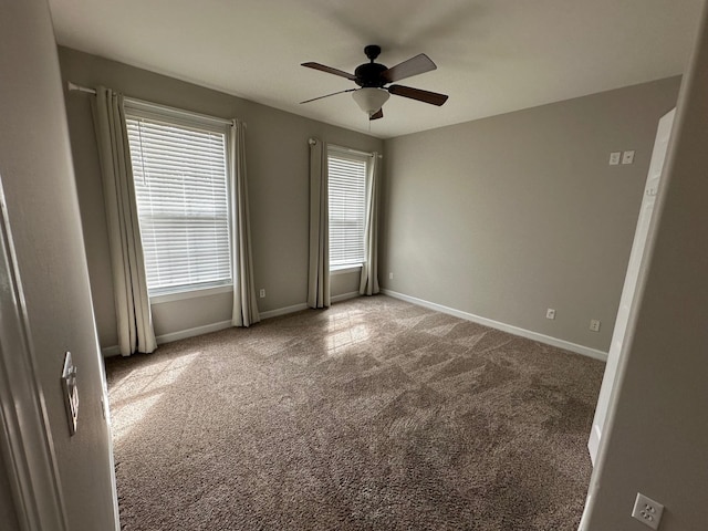 spare room featuring baseboards, a ceiling fan, and light colored carpet