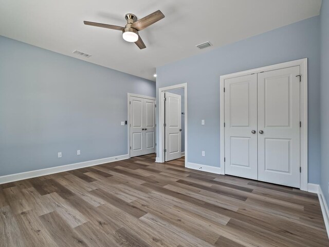 10356 Crystalline Ct, Tallahassee, FL 32305 - unfurnished bedroom with two closets, wood finished floors, baseboards, and ceiling fan