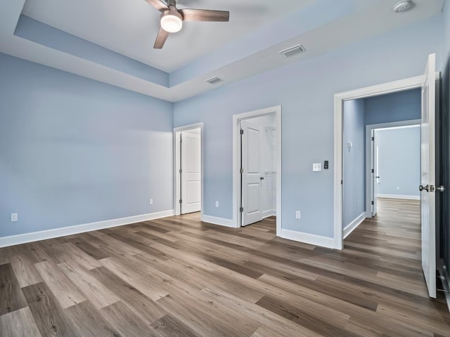 10356 Crystalline Ct, Tallahassee, FL 32305 - unfurnished bedroom with wood finished floors, baseboards, a tray ceiling, a ceiling fan, and a spacious closet