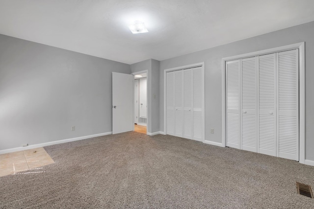 unfurnished bedroom with multiple closets and carpet floors