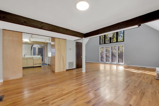 unfurnished living room with light wood-type flooring and beam ceiling