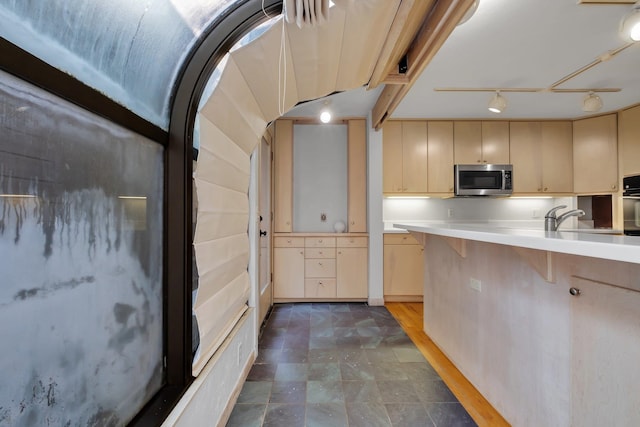 kitchen featuring cream cabinets, black oven, sink, a breakfast bar, and rail lighting