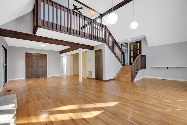 unfurnished living room featuring high vaulted ceiling, light wood-type flooring, ceiling fan, and beam ceiling