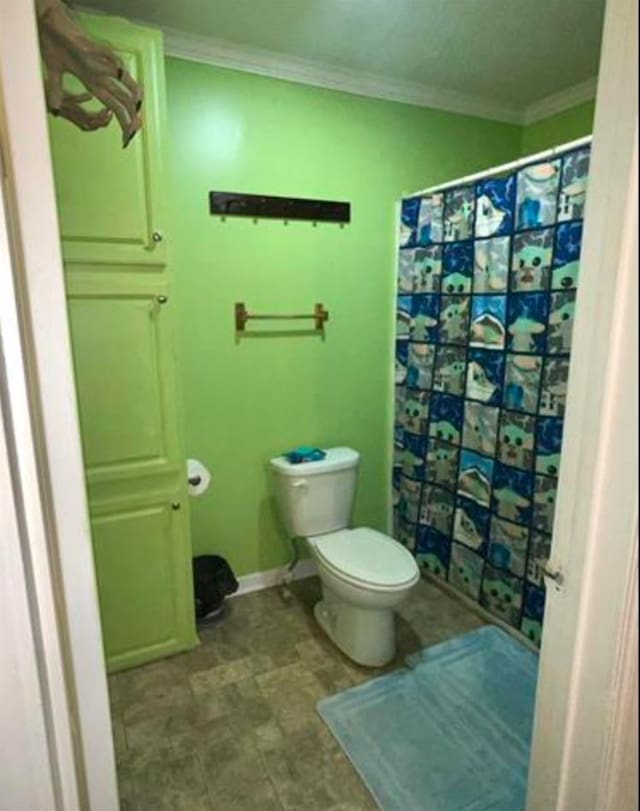 bathroom with walk in shower, crown molding, and toilet