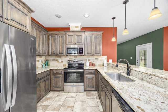 kitchen with tasteful backsplash, appliances with stainless steel finishes, light stone countertops, and a sink