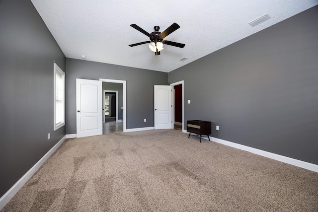 unfurnished bedroom featuring visible vents, carpet floors, a textured ceiling, and baseboards