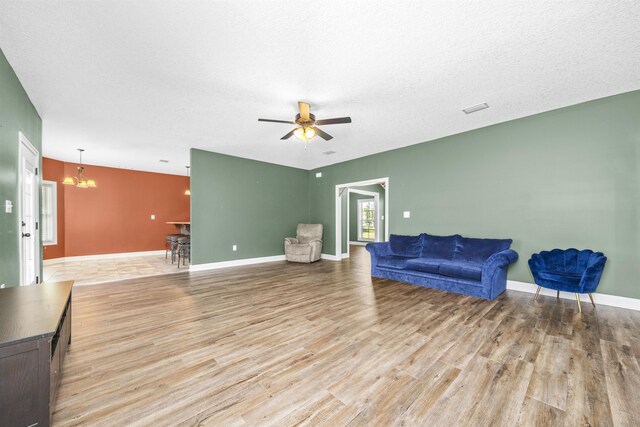 living area featuring visible vents, a textured ceiling, light wood-style flooring, and a ceiling fan