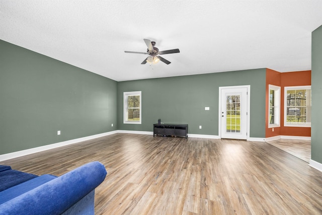 unfurnished living room featuring a healthy amount of sunlight, wood finished floors, and a ceiling fan