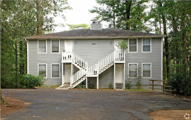 view of front facade with entry steps, stairs, and a chimney