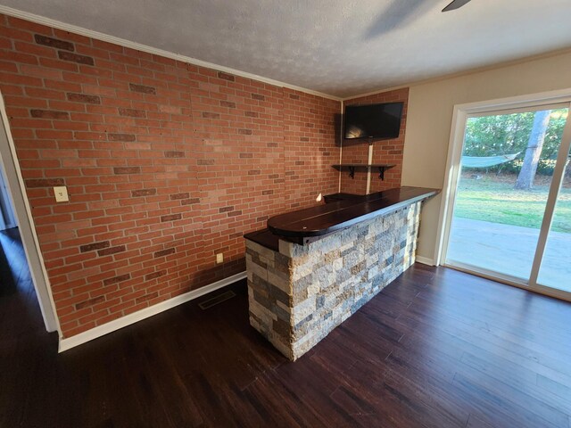 bar with brick wall, ornamental molding, dark wood-style flooring, and visible vents