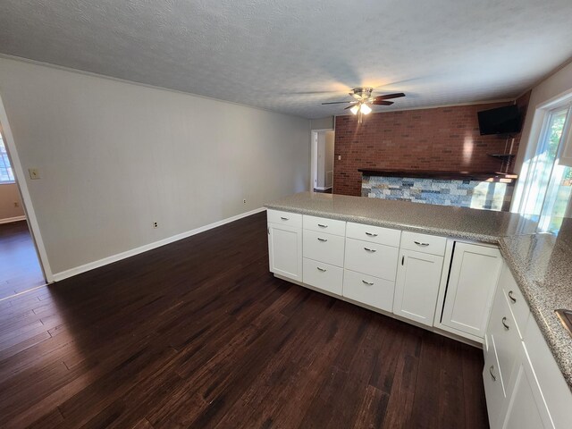 kitchen with baseboards, a textured ceiling, white cabinetry, and dark wood-style flooring