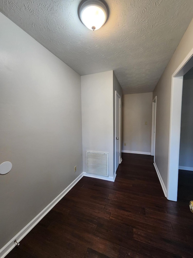 interior space featuring baseboards, visible vents, a textured ceiling, and hardwood / wood-style floors