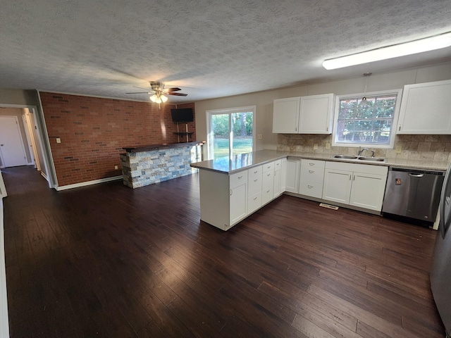 kitchen featuring a peninsula, a sink, white cabinetry, dark wood-style floors, and dishwasher