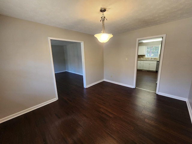 spare room with dark wood-type flooring and baseboards