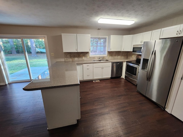 kitchen featuring tasteful backsplash, white cabinets, dark wood-style floors, a peninsula, and stainless steel appliances