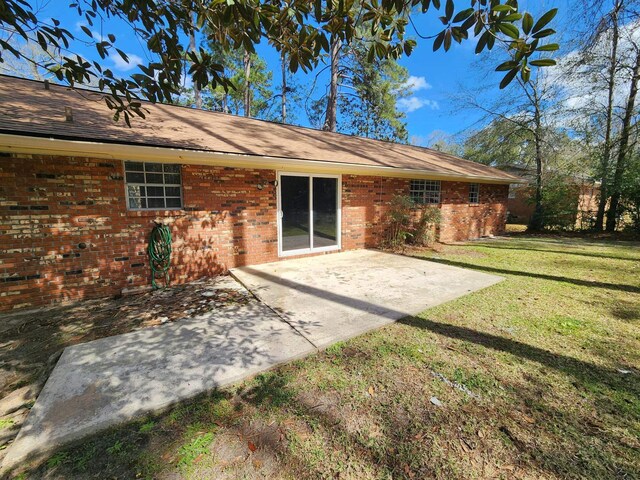 rear view of house featuring a yard, a patio, and brick siding