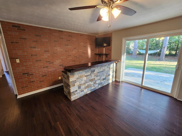 bar with brick wall, dark wood finished floors, and crown molding