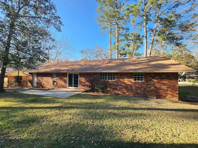 rear view of house featuring brick siding, a lawn, and a patio area