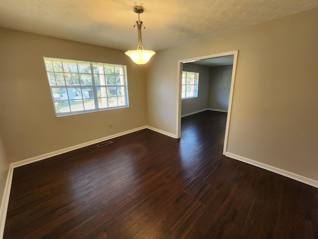 spare room featuring baseboards, visible vents, and dark wood-type flooring