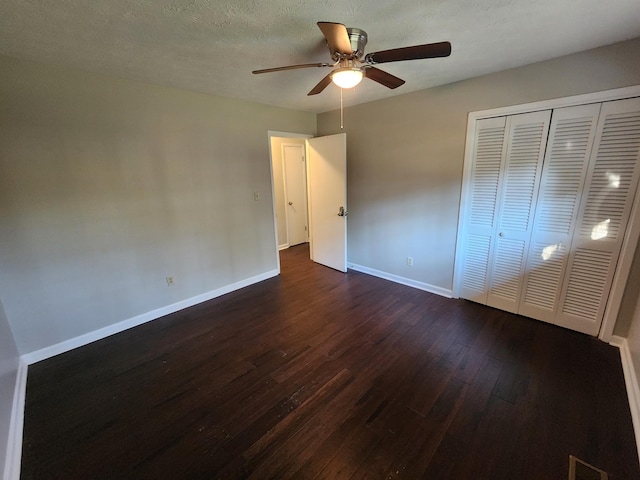 unfurnished bedroom featuring a closet, visible vents, dark wood-type flooring, a textured ceiling, and baseboards