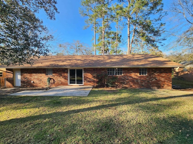 rear view of property featuring a yard, brick siding, and a patio