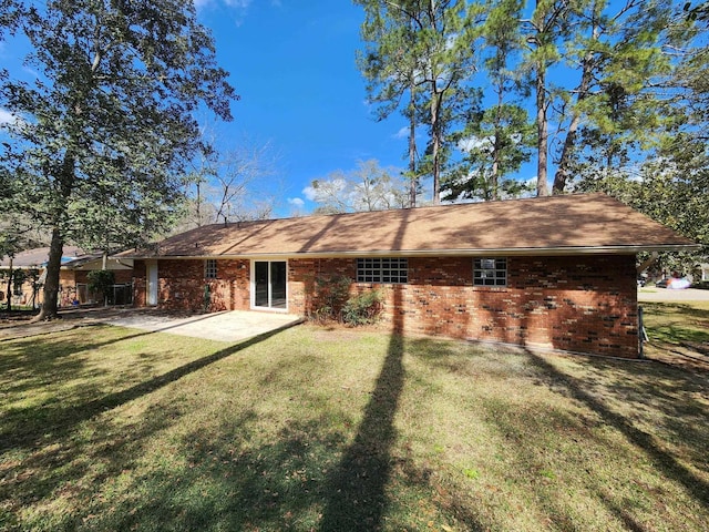 rear view of property featuring a yard, brick siding, and a patio