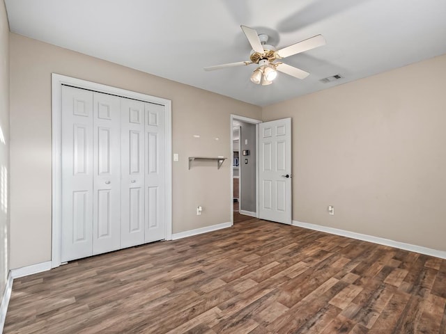 unfurnished bedroom with dark wood-type flooring, a closet, and ceiling fan