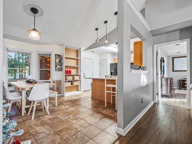 kitchen with lofted ceiling, refrigerator with ice dispenser, built in shelves, decorative light fixtures, and kitchen peninsula