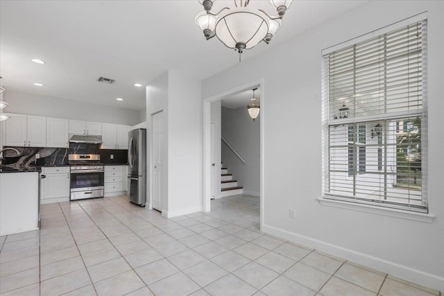 2123 Fernleigh Dr, Tallahassee, FL 32311 - kitchen with appliances with stainless steel finishes, under cabinet range hood, white cabinetry, backsplash, and dark countertops