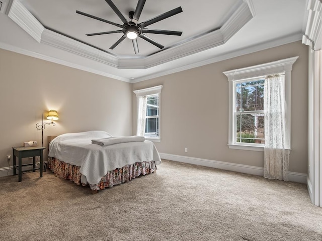 carpeted bedroom with multiple windows, ornamental molding, ceiling fan, and a tray ceiling