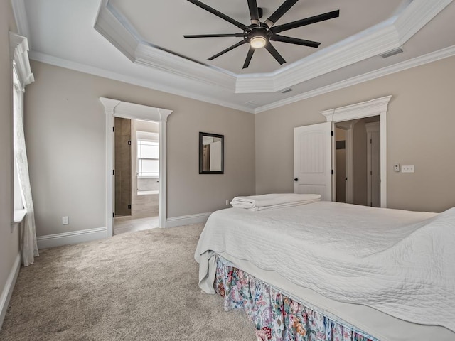 carpeted bedroom featuring a raised ceiling, crown molding, ceiling fan, and ensuite bath