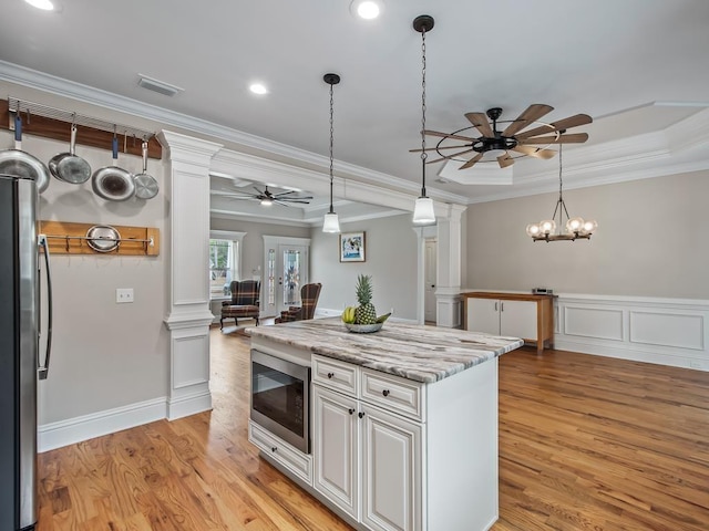 kitchen featuring appliances with stainless steel finishes, light stone countertops, decorative columns, and white cabinets