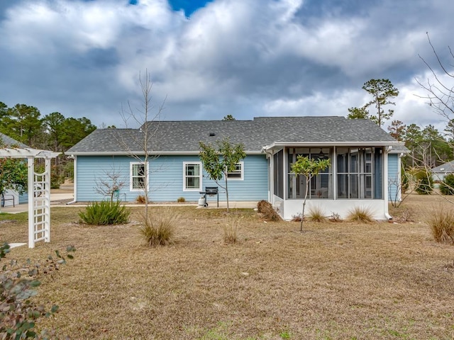 rear view of property featuring a sunroom and a lawn