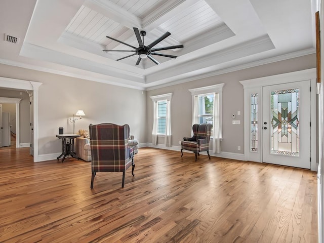 living area with crown molding, a tray ceiling, ceiling fan, and hardwood / wood-style flooring