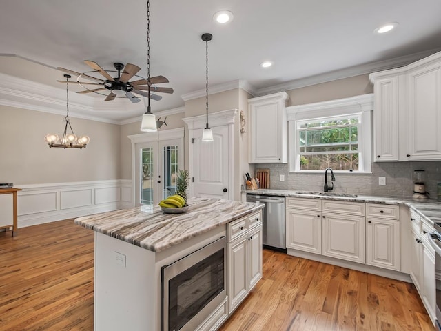 kitchen featuring built in microwave, stainless steel dishwasher, white cabinets, and a kitchen island