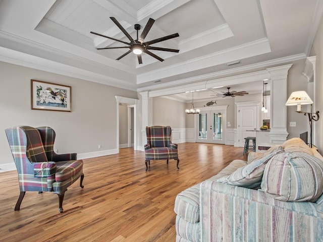 bedroom featuring decorative columns, a raised ceiling, ornamental molding, and light hardwood / wood-style flooring