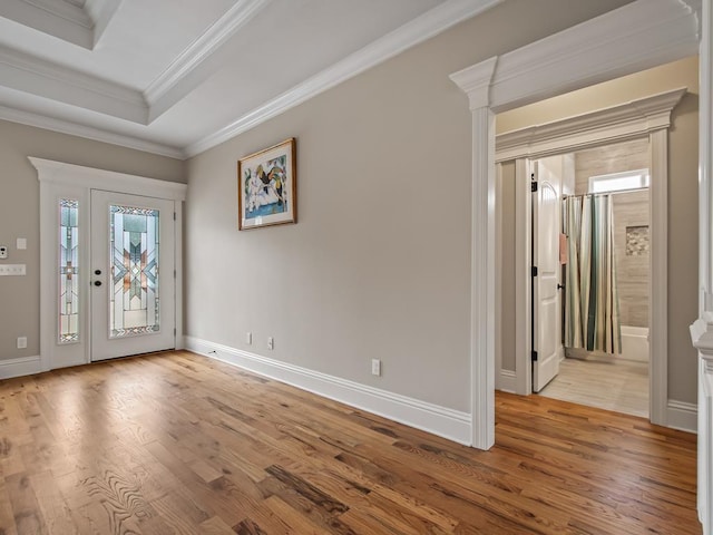 foyer entrance featuring ornamental molding, a raised ceiling, and light hardwood / wood-style floors