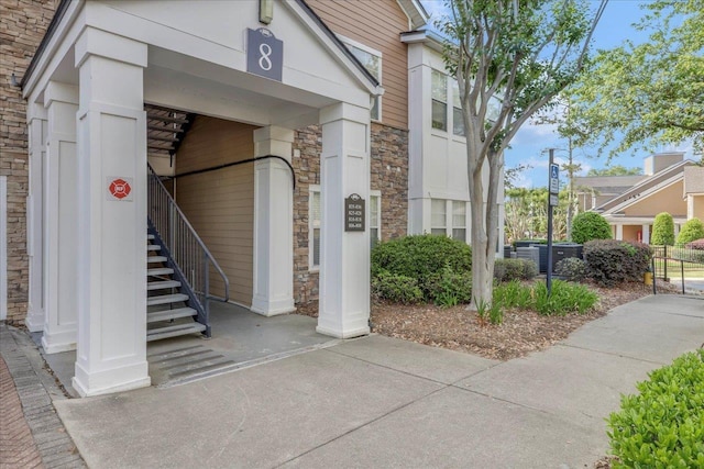 view of exterior entry with central air condition unit and stone siding