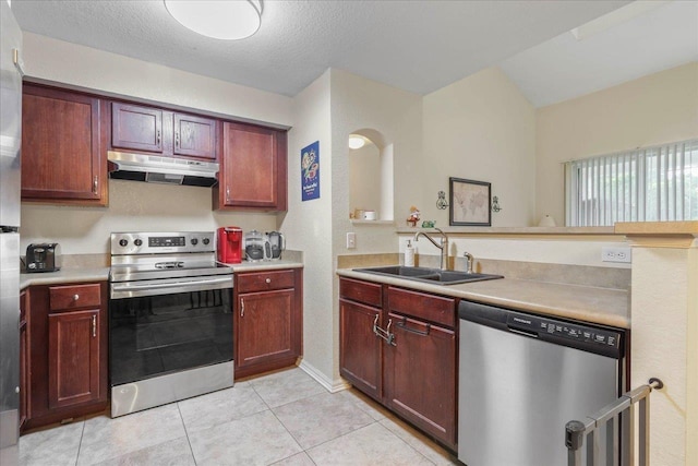 kitchen featuring stainless steel appliances, under cabinet range hood, light countertops, and a sink