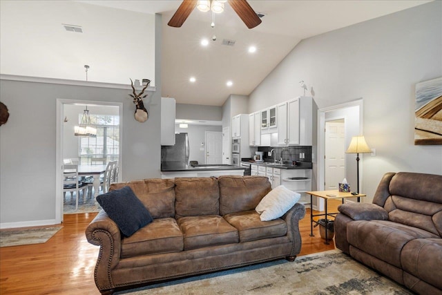 living room featuring ceiling fan, light hardwood / wood-style floors, sink, and high vaulted ceiling