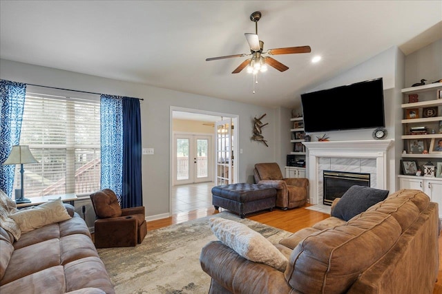 living room with a tile fireplace, french doors, light hardwood / wood-style floors, and ceiling fan