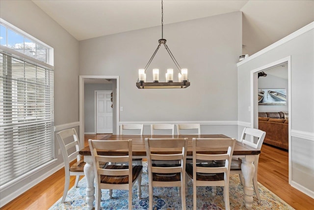 dining space featuring wood-type flooring, vaulted ceiling, and a notable chandelier