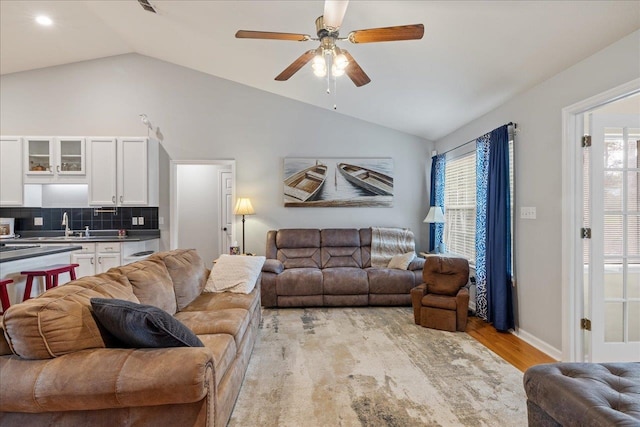 living room featuring light hardwood / wood-style flooring, vaulted ceiling, and ceiling fan