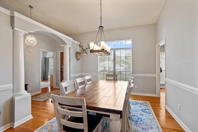 dining room featuring ornate columns, a chandelier, and light hardwood / wood-style floors