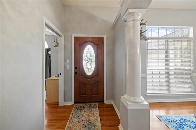 foyer with ornate columns, a healthy amount of sunlight, and wood-type flooring